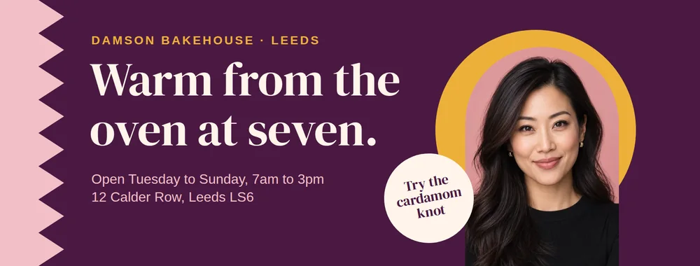 A wide plum Facebook cover with a blush zig-zag edge, the cream serif headline Warm from the oven at seven., opening hours and an address in blush, a round cream sticker reading Try the cardamom knot, and an East Asian woman in an arch in front of a mustard circle.