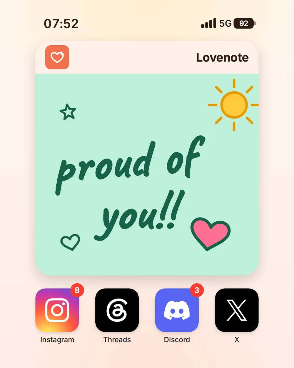 A peach iPhone home screen at 07:52 with a large widget headed Lovenote holding a proud of you doodle with a sun and a pink heart on mint, above the Instagram, Threads, Discord, and X icons.
